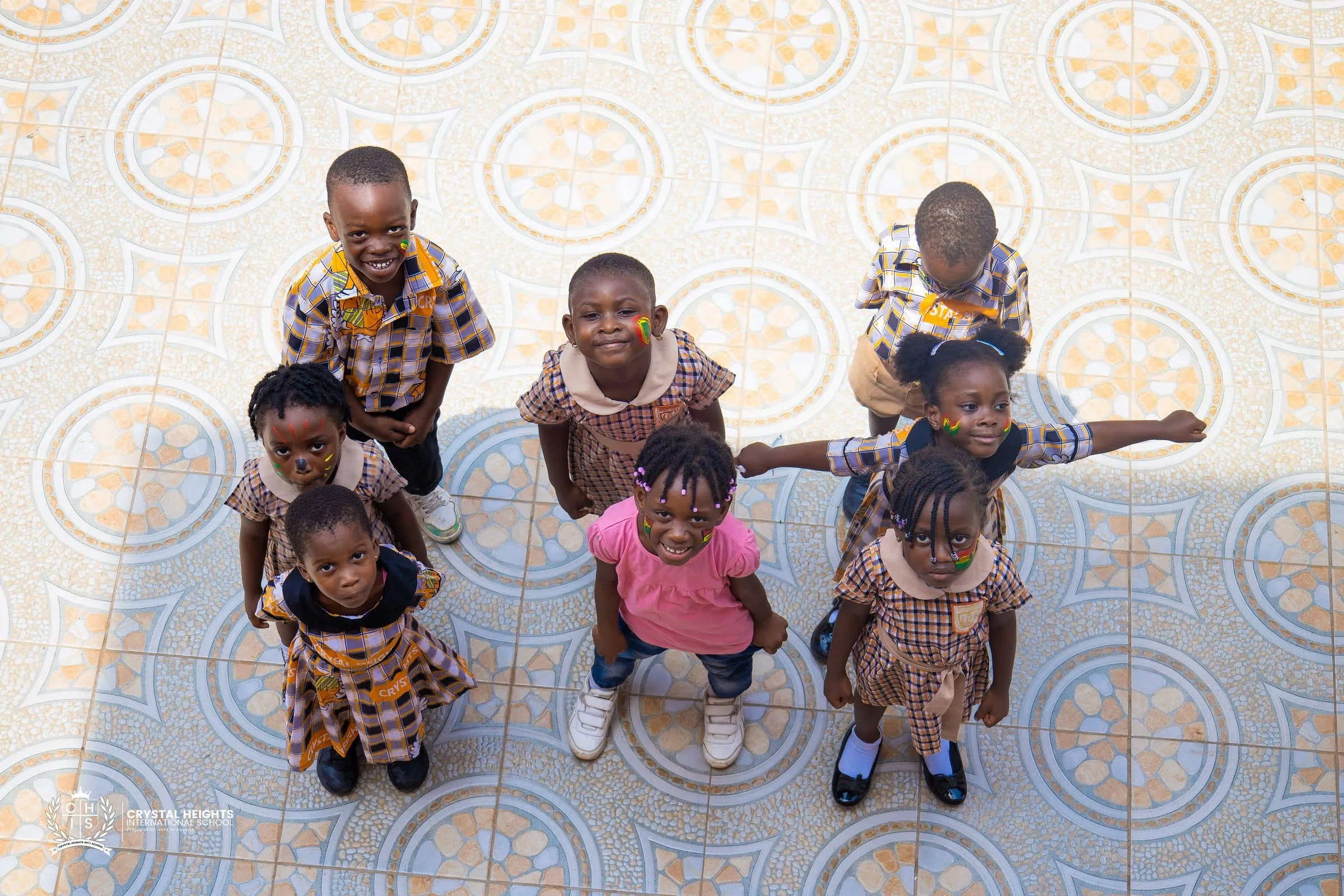 Early years pupils holding Ghanaian flags on the school astroturf