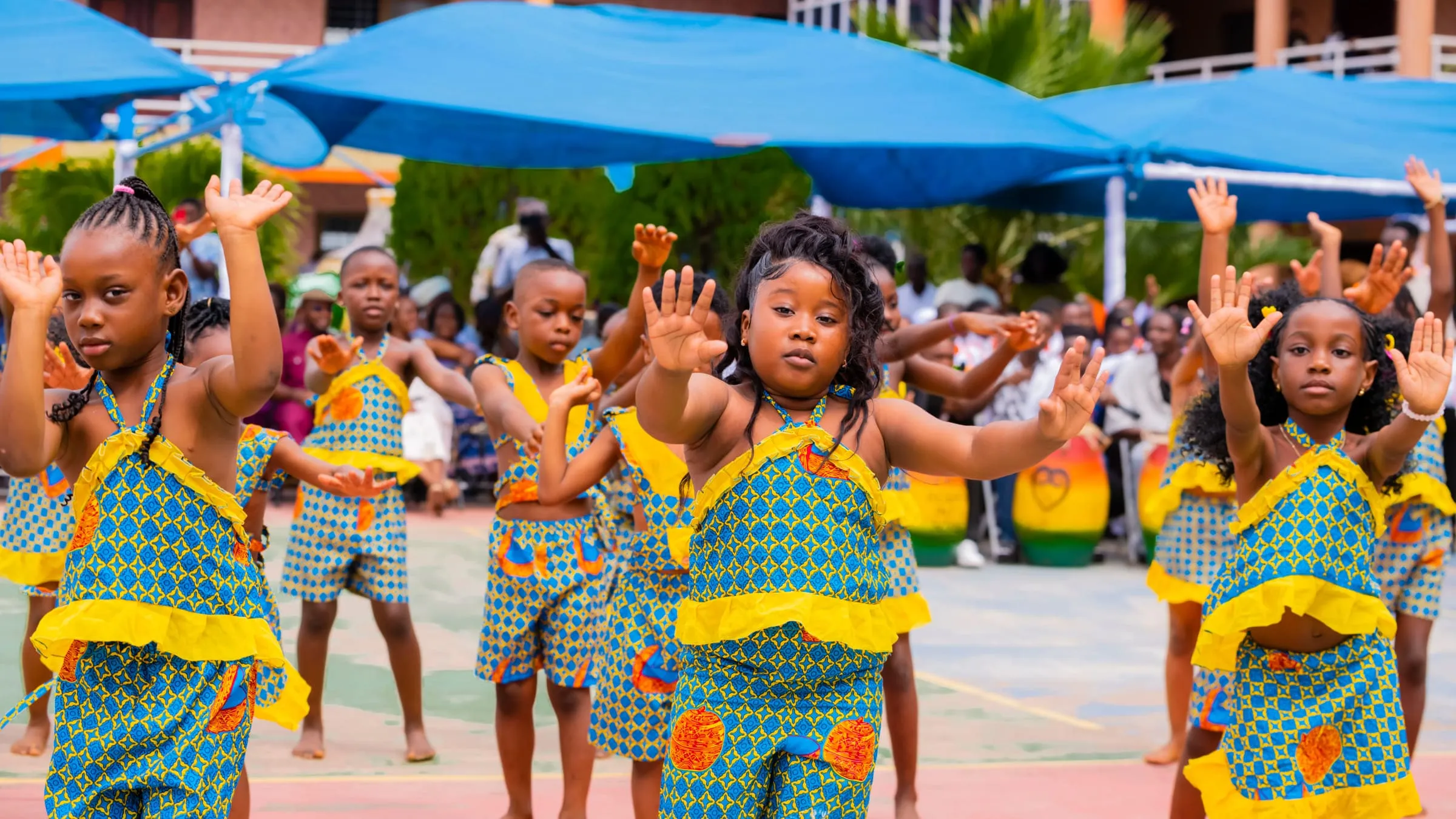 Crystal Heights early years pupils dancing outdoors in Ghanaian print at Speech and Prize Giving