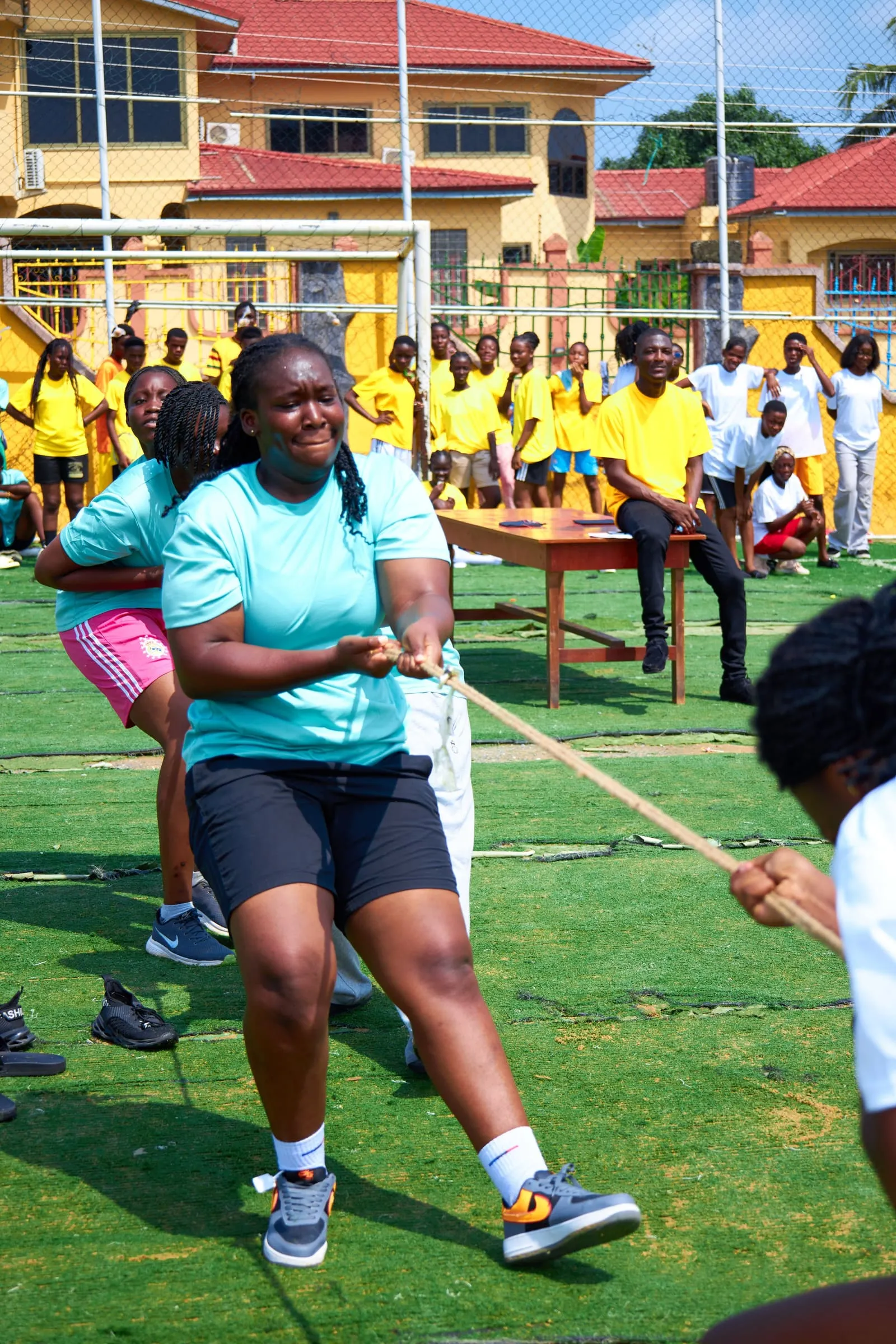 Pupils in house colours pulling on a rope during a tug of war on the school field